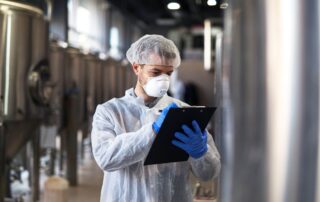 Clipboard-technologist-white-uniform-checking-quality-face-mask-production-factory-tank-inspection